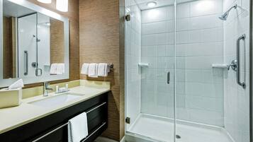 A modern bathroom with a glass-enclosed shower, a vanity with a sink, and a mirror.