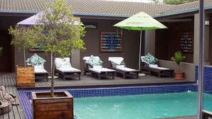 A poolside area with lounge chairs and a small tree.