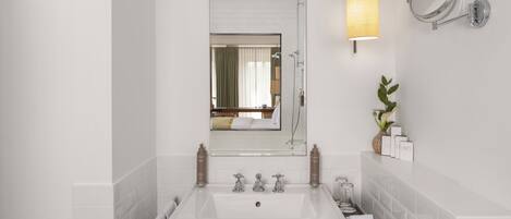 A modern bathroom with a large mirror, two sinks, a shower, and a towel rack.
