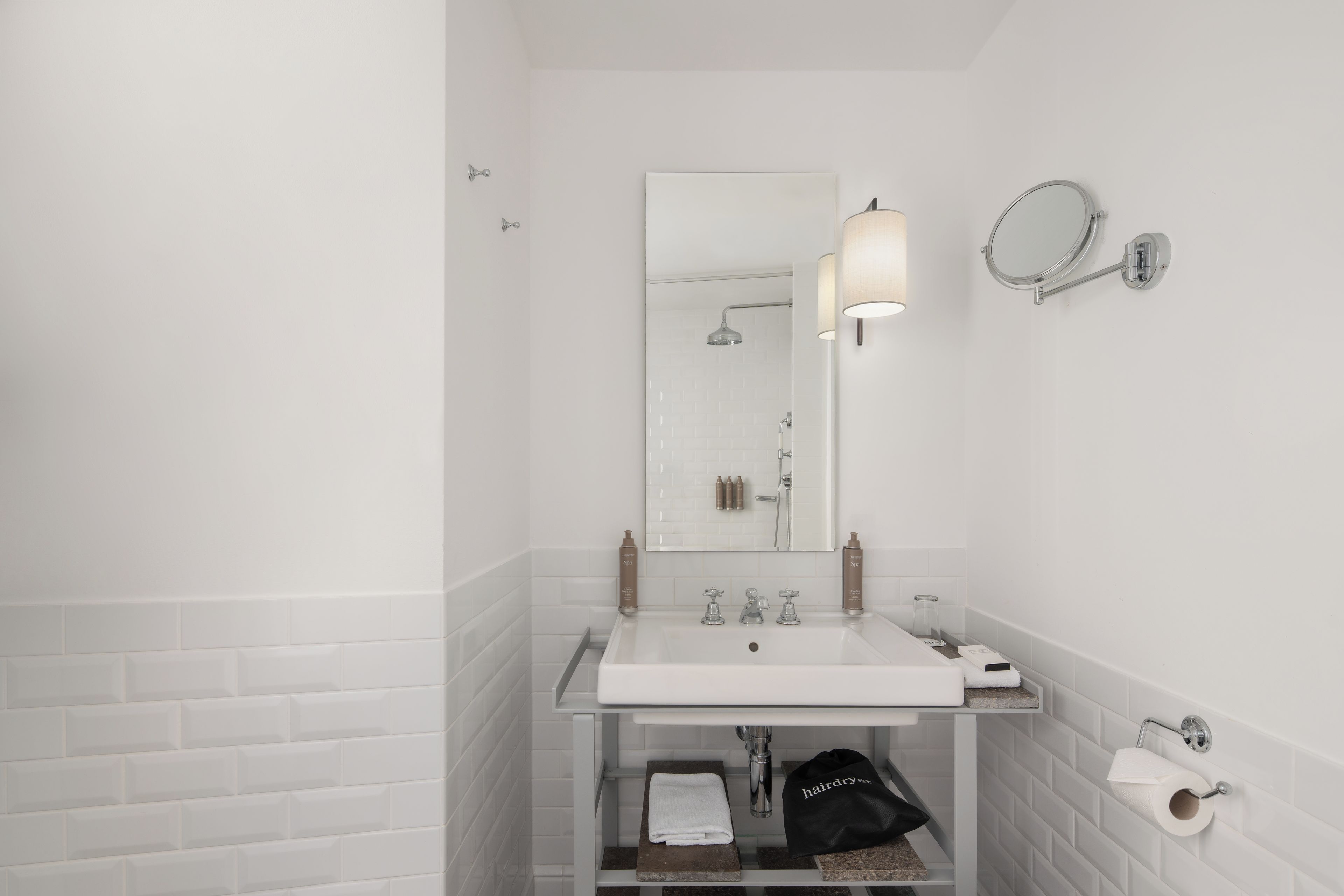 A modern bathroom with a white sink, mirror, and two towel racks.