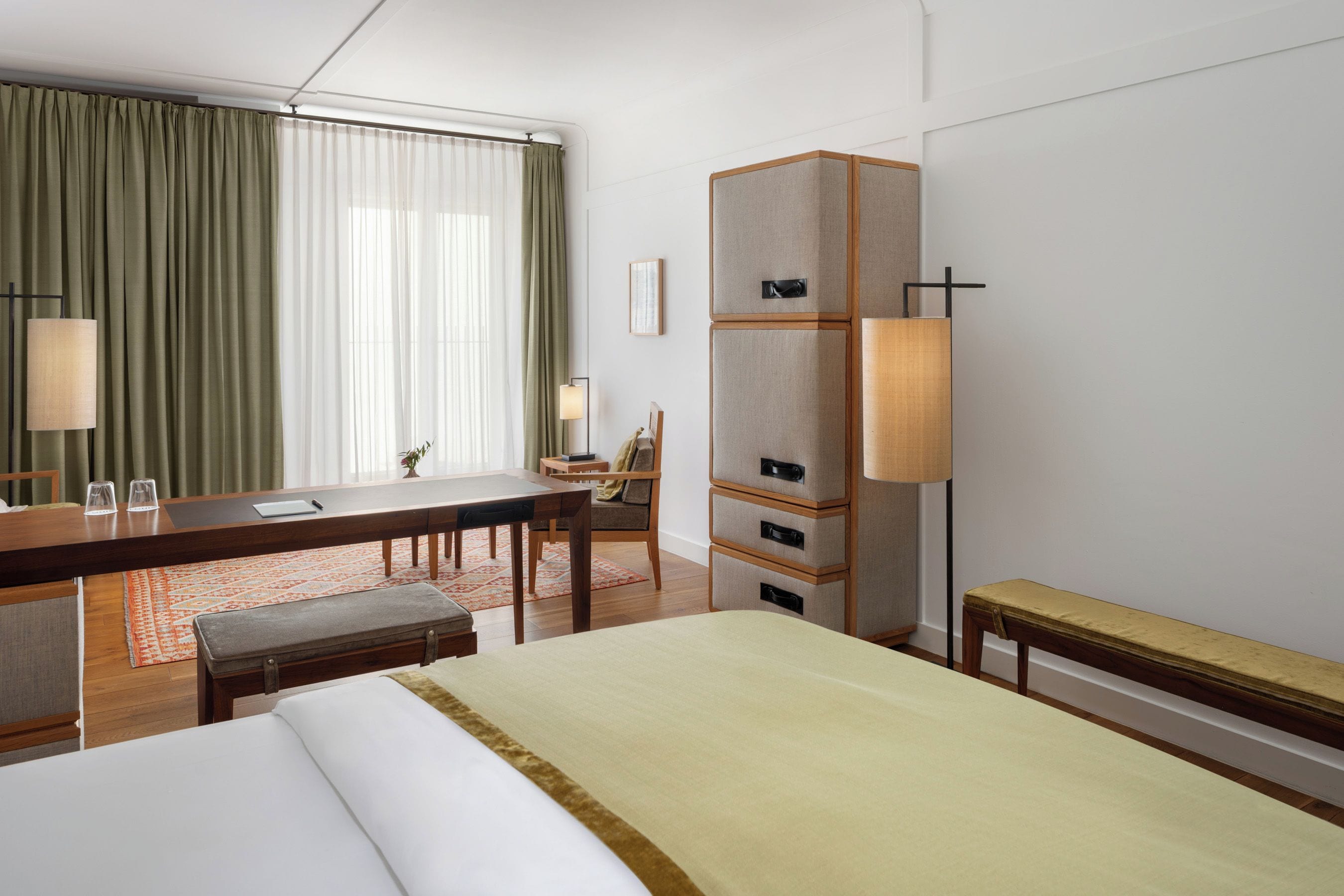 A hotel room with a bed, desk, chair, and a wardrobe.