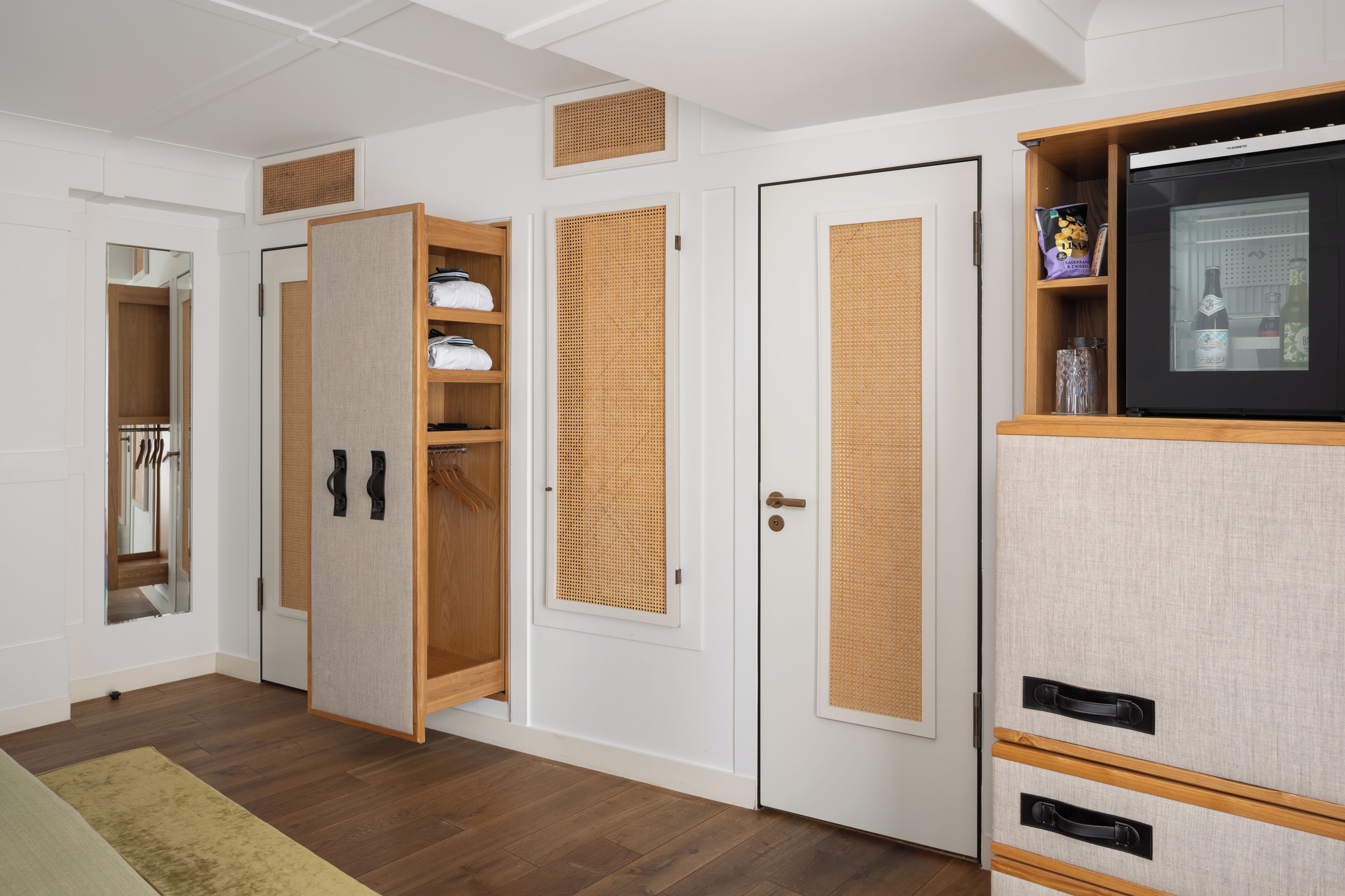 A room with a wardrobe, a television, and a door with a woven panel.