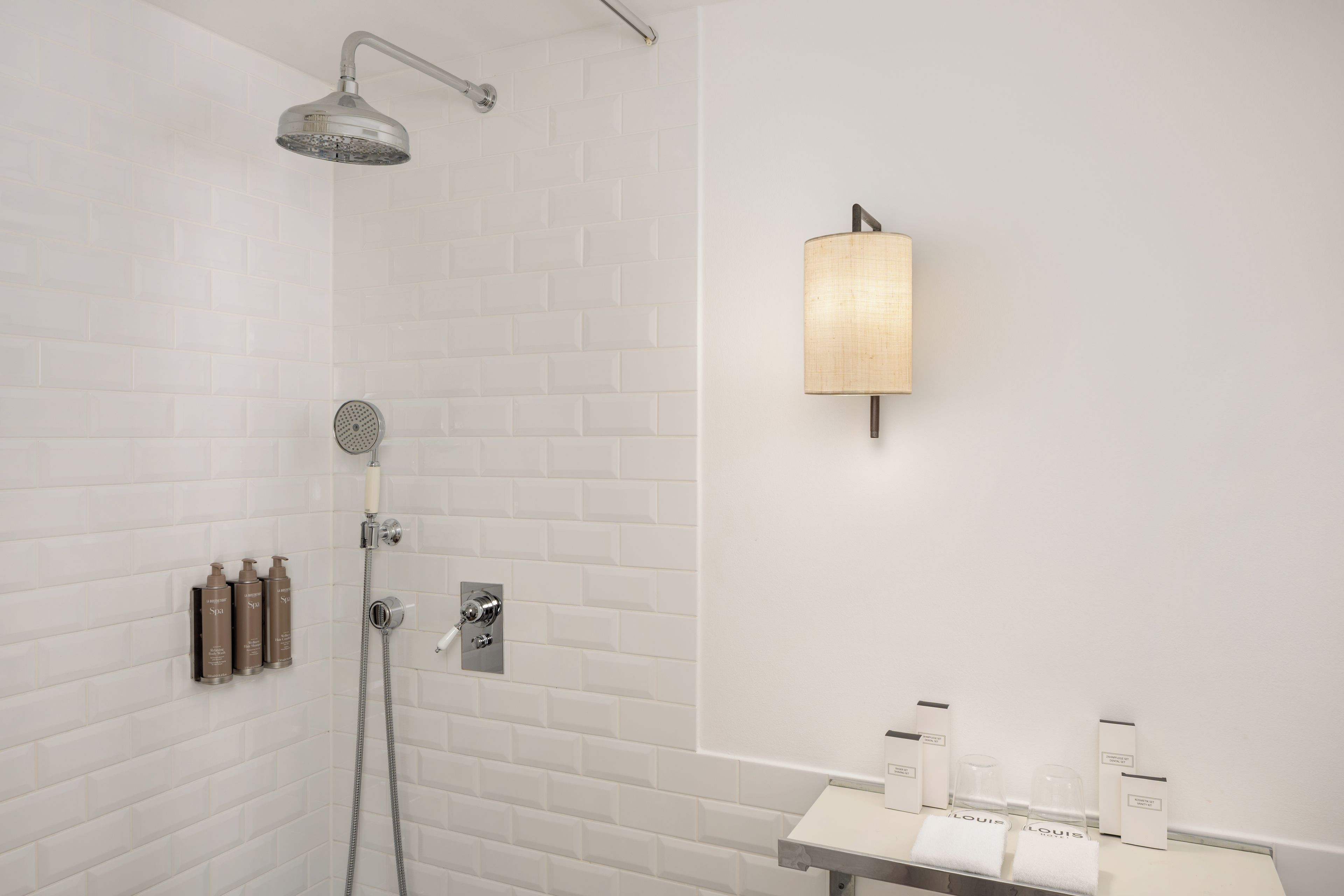 A modern bathroom with a shower, a towel rack, and toiletries.