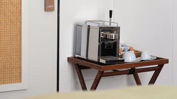 Eine kompakte Kaffeemaschine auf einem Holztisch mit zwei weißen Tassen und einer Eierplatte.