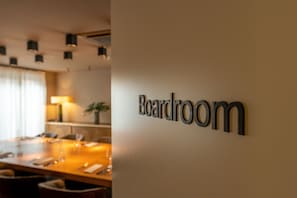 Enjoy meals in the Boardroom, equipped with a long dining table and comfortable seating.