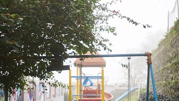 Enjoy a peaceful family playtime in this serene outdoor space with a swing set, slide, and climbing structure.