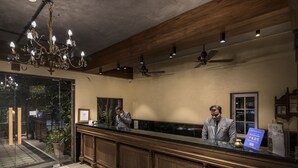 Una recepción con candelabro, ventiladores de techo y un cartel que indica las tarifas de las habitaciones.