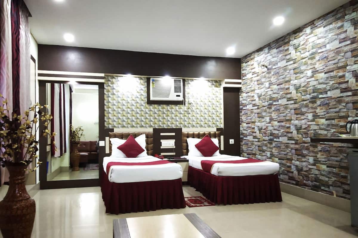 A hotel room with two beds, a stone wall, a mirror, and a potted plant.