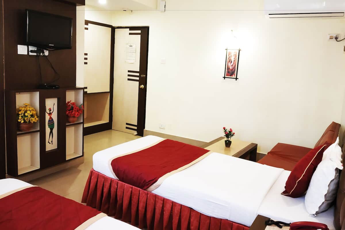 A hotel room with two beds, a TV, an air conditioner, and a door leading to another room.