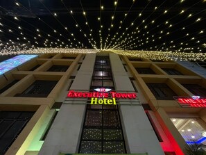 Hotel Executive Tower, con fachada moderna, múltiples ventanas y un letrero que indica un restaurante.