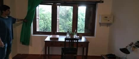 A room with a desk, chair, and a window with curtains.