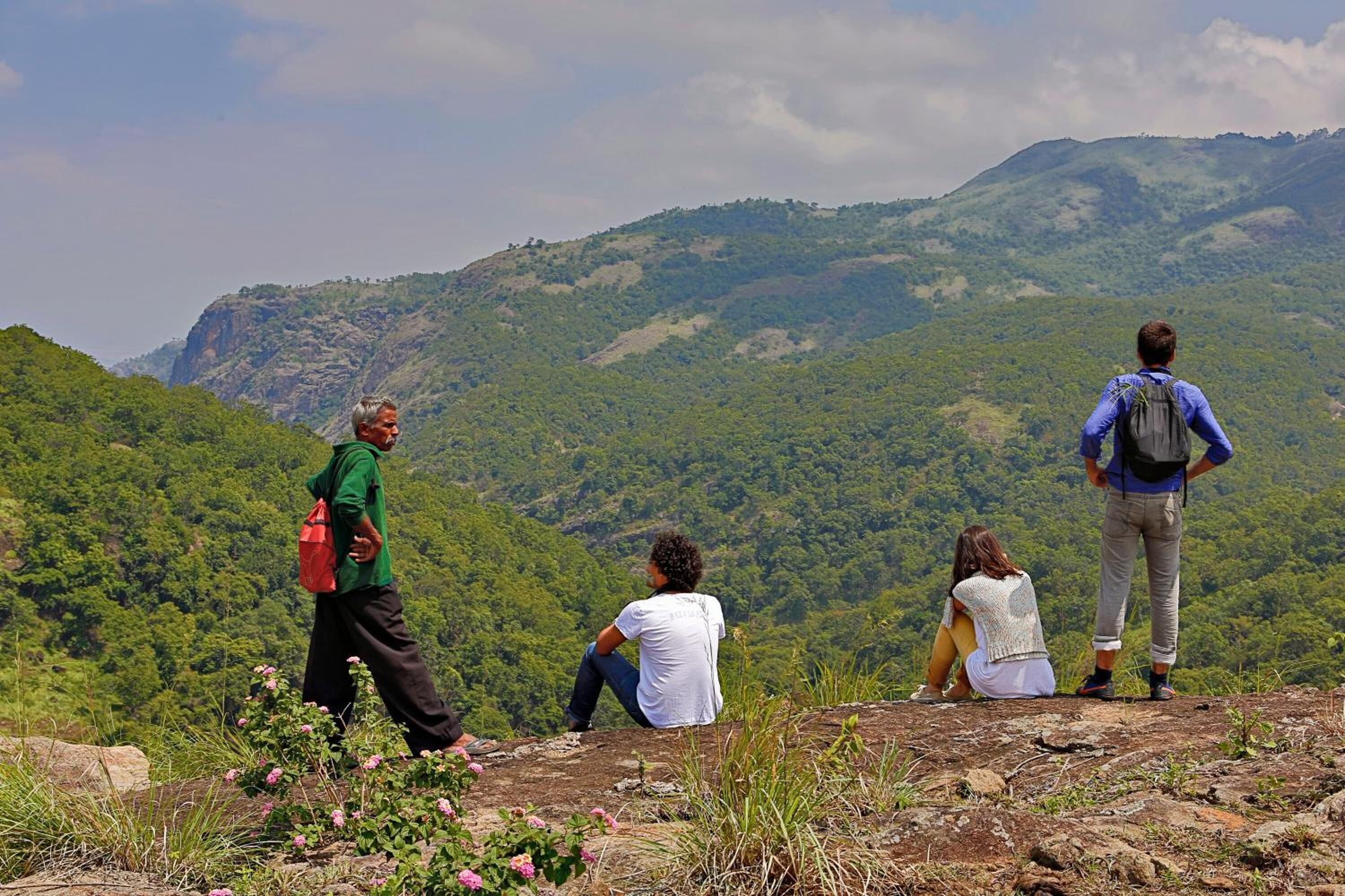 A group of people on a mountain ridge with a view of a forested valley.