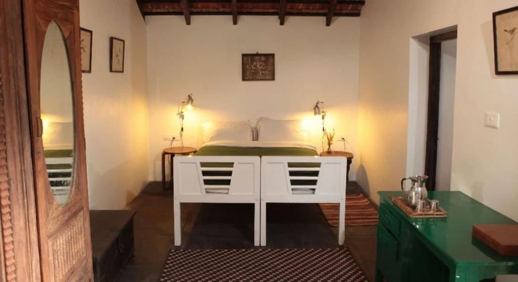 Un dormitorio con cama, lámparas de noche, una mesa verde y un espejo.