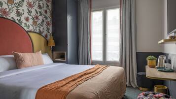Habitación de hotel con una cama grande, un escritorio con una planta y cortinas.