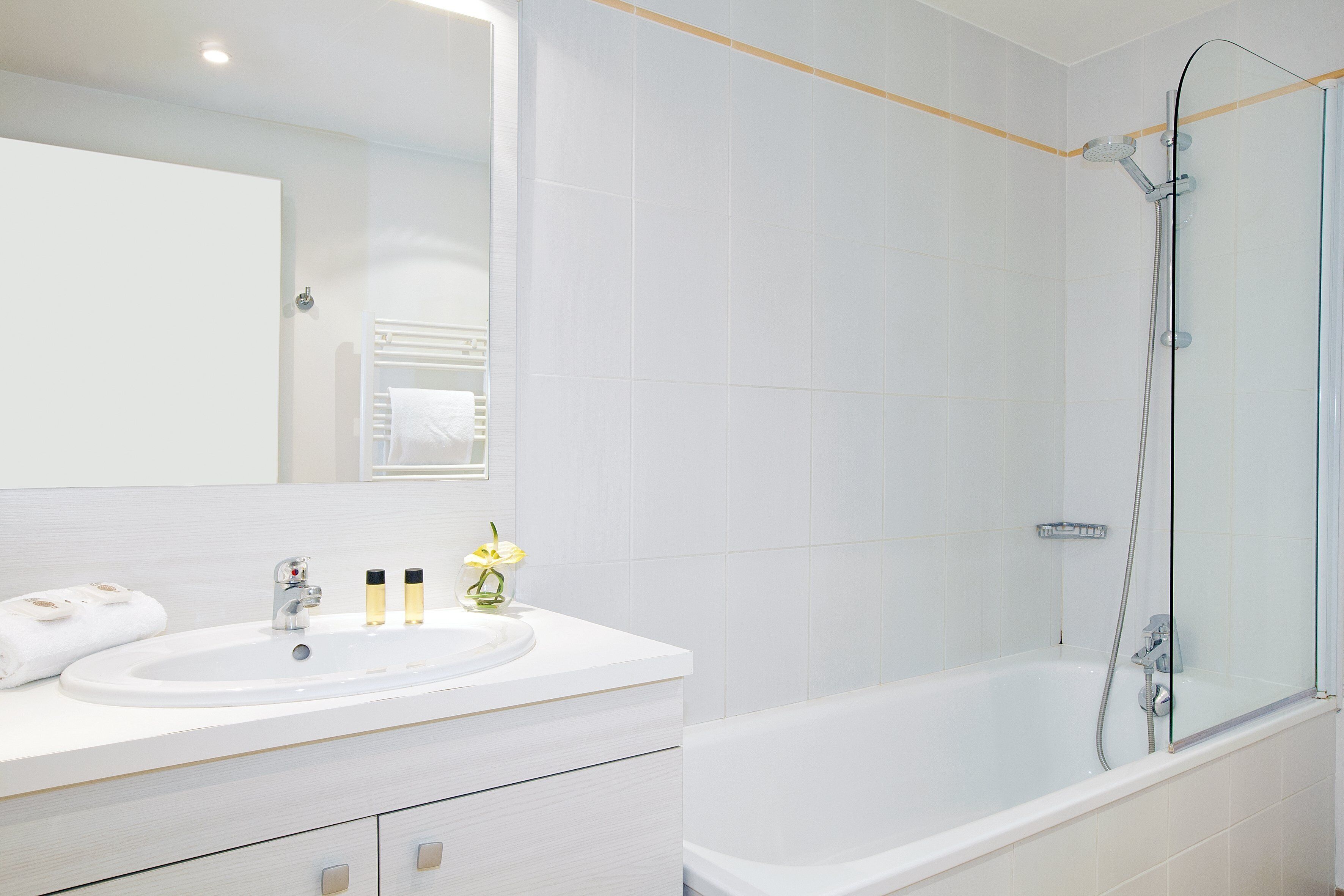Un baño moderno con un tocador blanco, un espejo grande, una bañera y una ducha con mampara de vidrio.