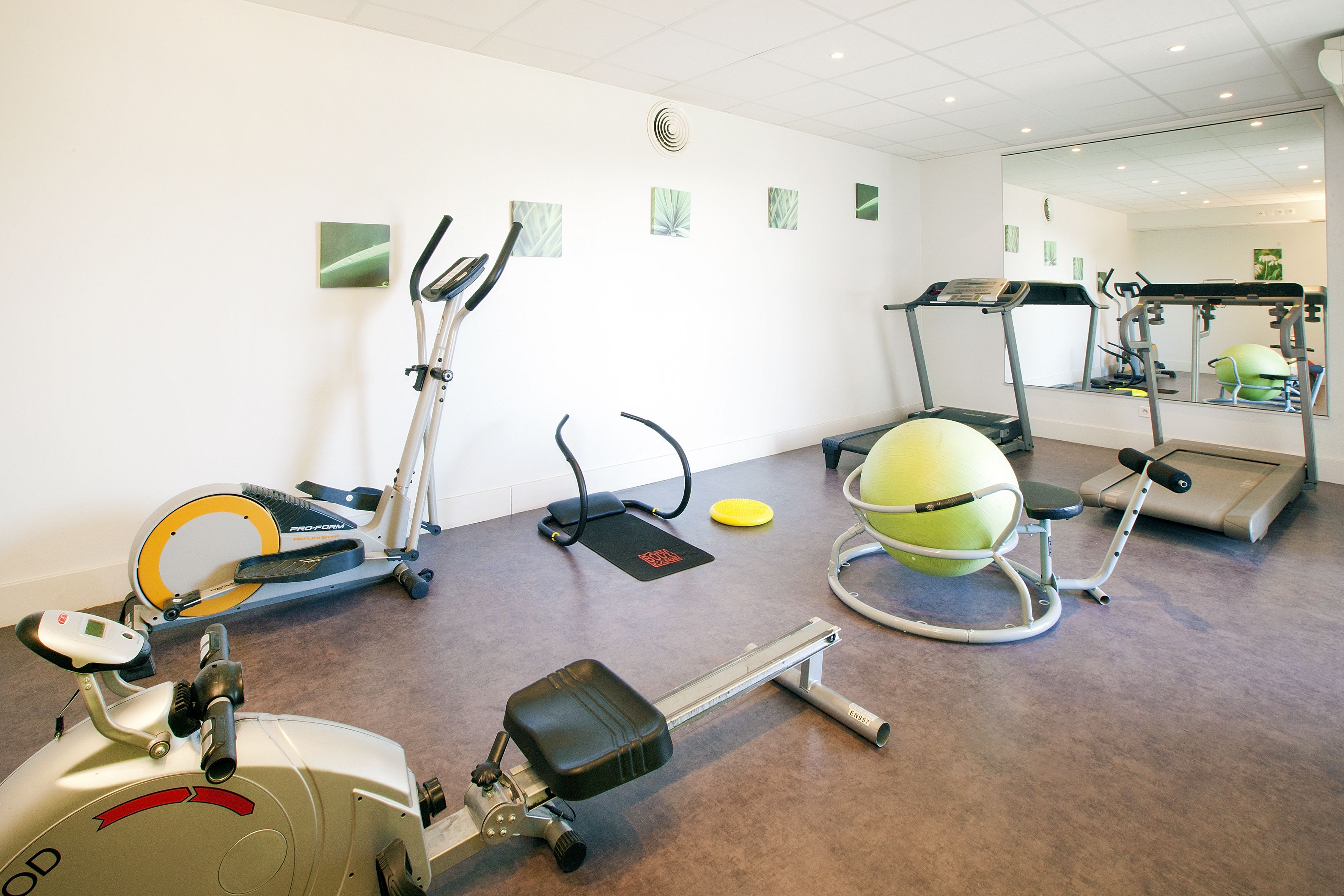 A gym with stationary bikes, elliptical machines, a treadmill, and a rowing machine.