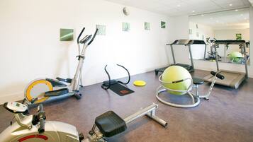 A gym with stationary bikes, elliptical machines, a treadmill, and a rowing machine.