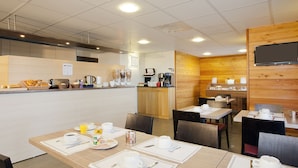 A breakfast area with tables set for dining, a coffee station, and a television mounted on the wall. - Séjours & Affaires Gex Les Rives du Leman (Gex)