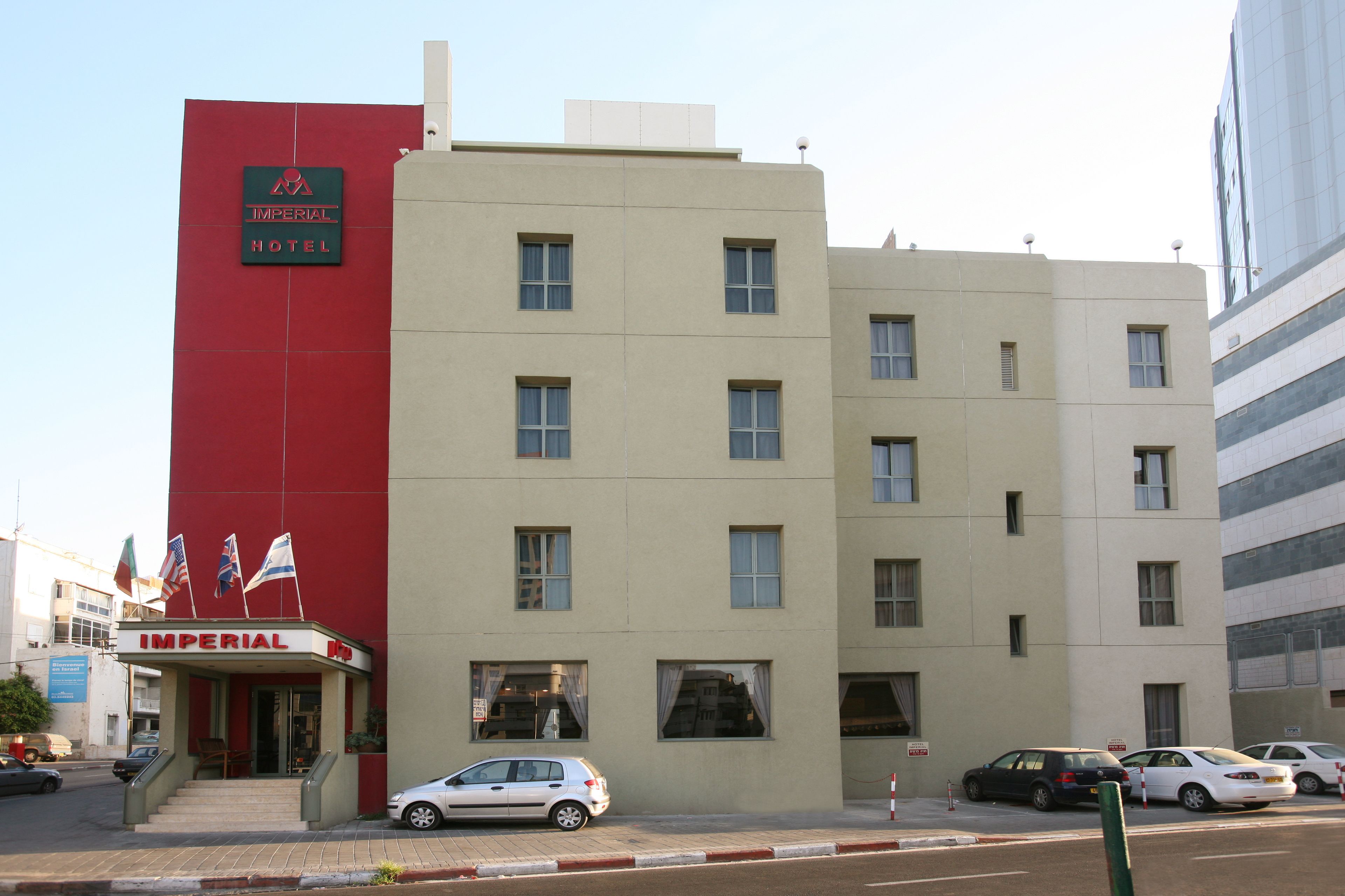 Un hotel con fachada roja y beige, numerosas ventanas y banderas.