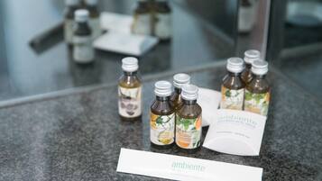 Una encimera de baño con botellas de gel de ducha y champú, un folleto y un cartel con la palabra 'ambiente'.