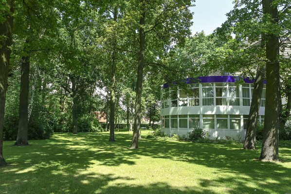 Un edificio moderno con grandes ventanales rodeado de exuberante vegetación y árboles.