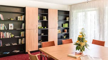 Een moderne bibliotheek met houten boekenkasten, een grote tafel en comfortabele stoelen.