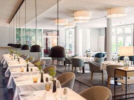 Um restaurante moderno com mesas compridas, cadeiras e iluminação pendente.