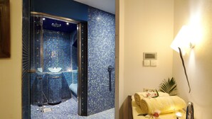 A bathroom with a blue-tiled shower area, a sink, and a mirror. - VITALHOTEL ambiente (Bad Wilsnack)