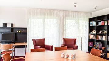 Uma sala de reuniões moderna com uma mesa de madeira, cadeiras de couro, uma estante e uma mesa com um computador.