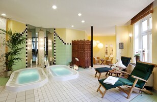 Uma área de spa com duas banheiras de hidromassagem, um separador de madeira e um espaço de estar com cadeiras.