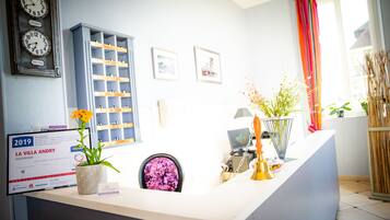 A reception desk with a clock, framed pictures, and a sign.