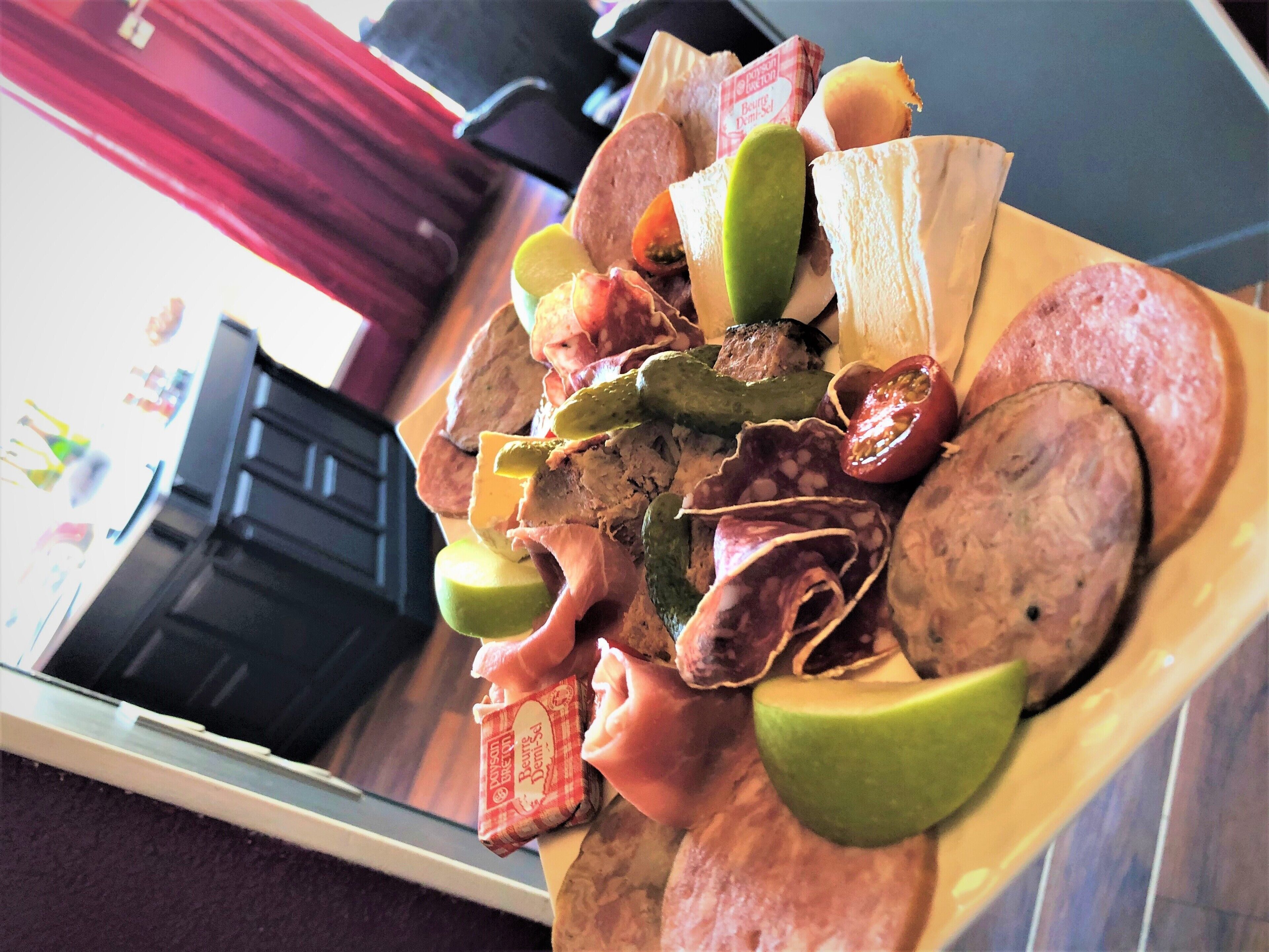 A plate of assorted meats and cheeses with lime wedges.