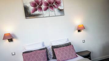 A hotel room with a bed, two bedside lamps, a nightstand, a phone, and a painting on the wall.