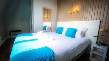 Habitación de hotel con una cama grande, una mesita de noche, un espejo y una lámpara fijada a la pared.