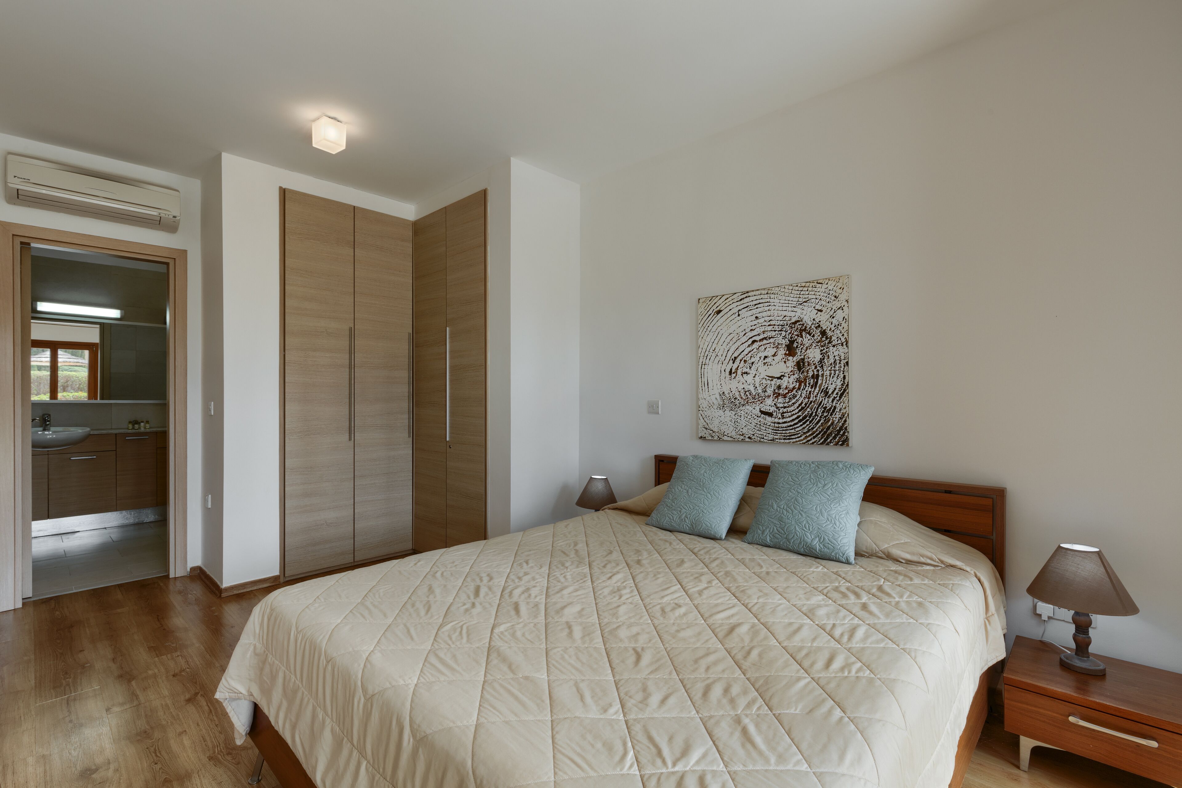 A bedroom with a bed, bedside table, lamp, and a wardrobe.