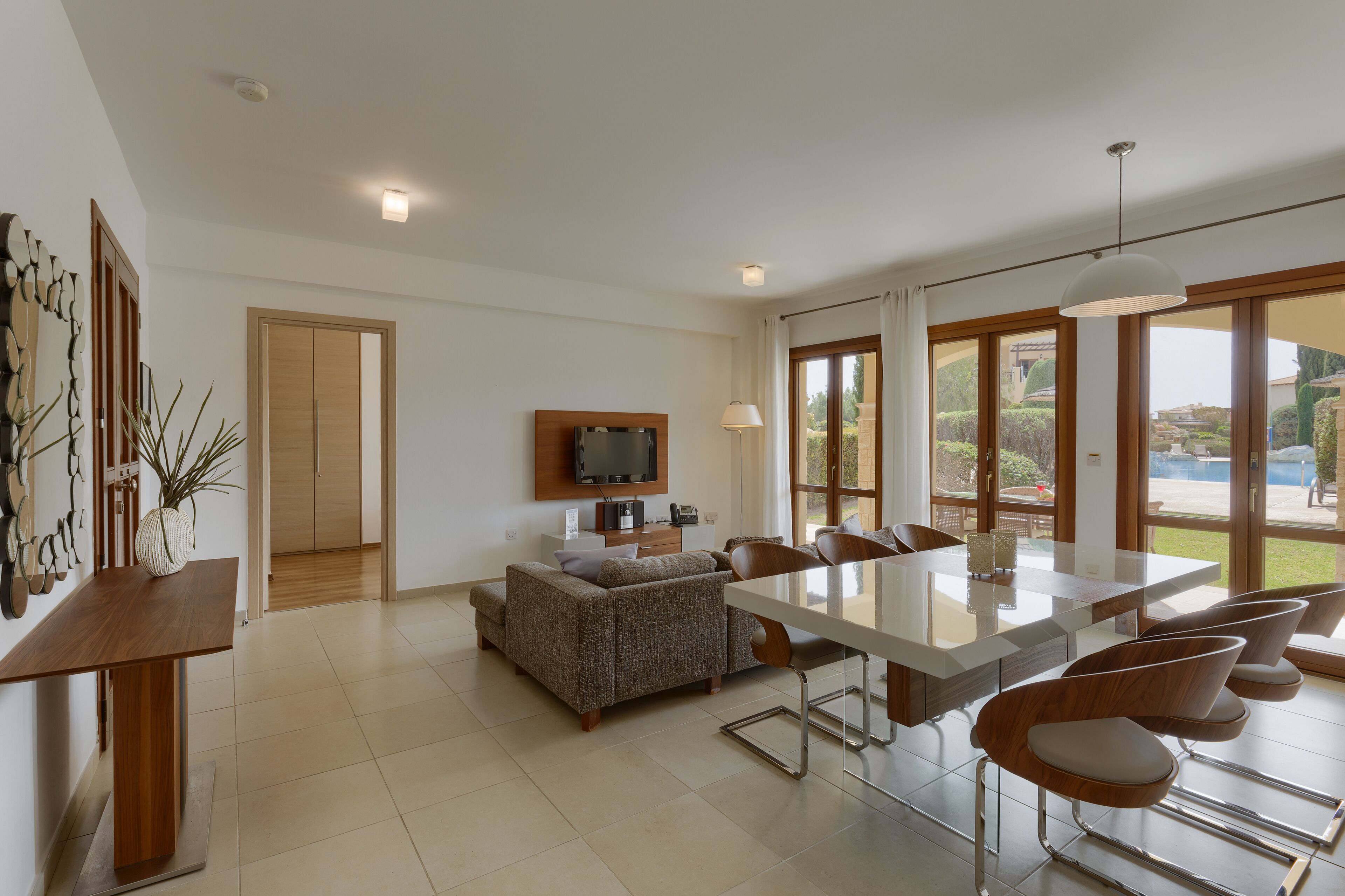 A spacious living area with a dining table, sofa, and TV.