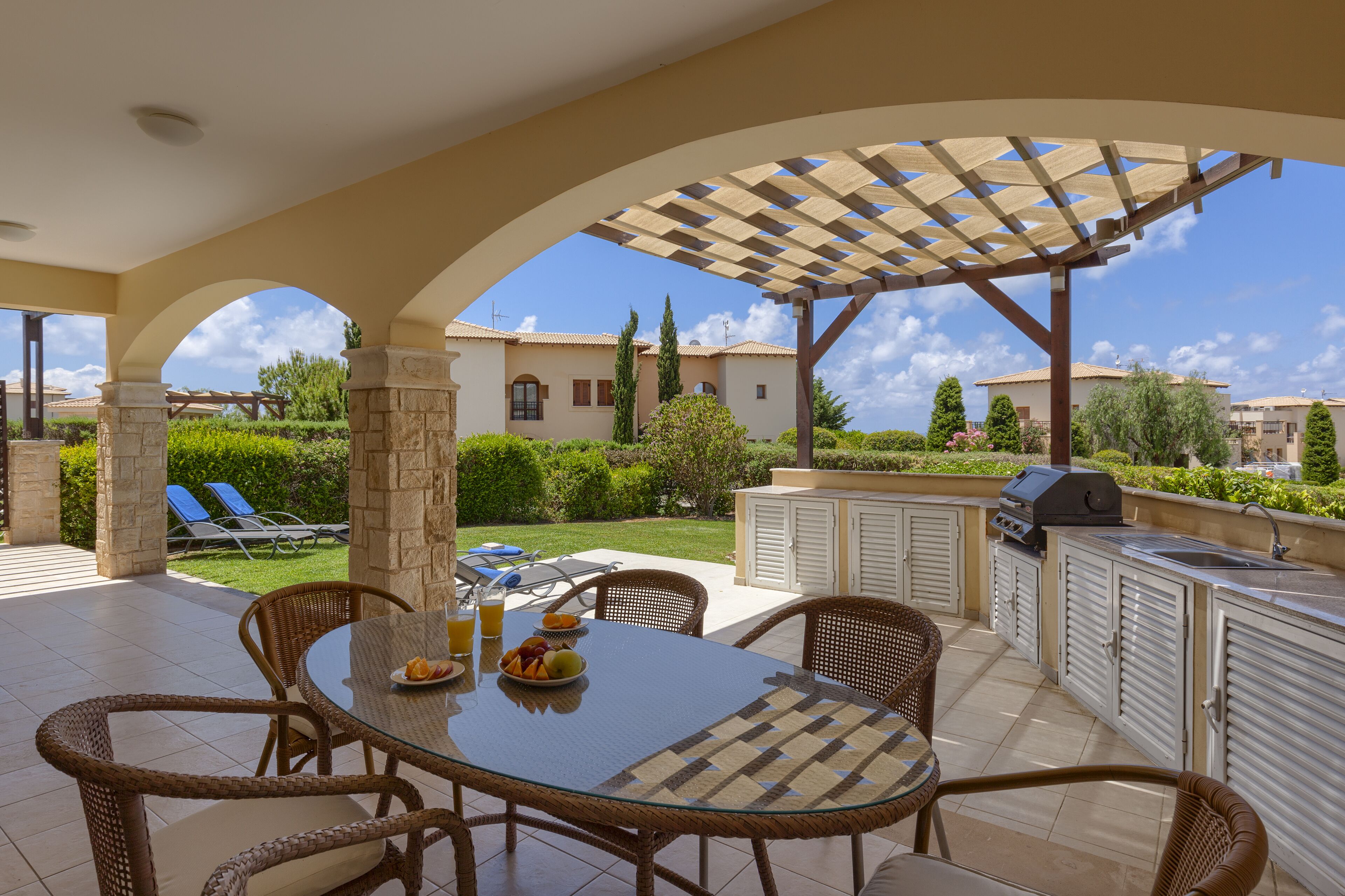 Un patio al aire libre con una mesa de comedor, sillas y zona de barbacoa.