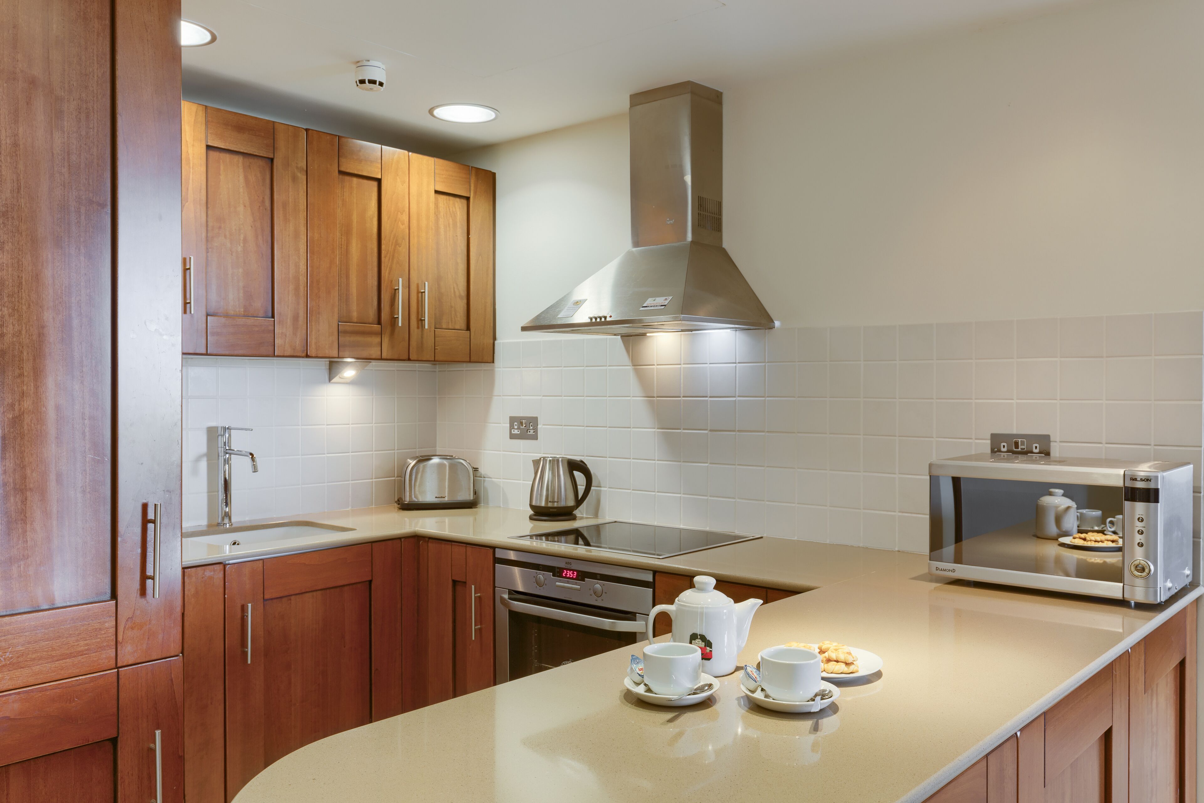 A modern kitchen with wooden cabinets, stainless steel appliances, and a built-in microwave.