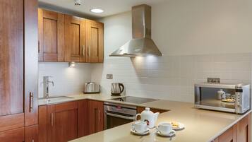 A modern kitchen with wooden cabinets, stainless steel appliances, and a built-in microwave.