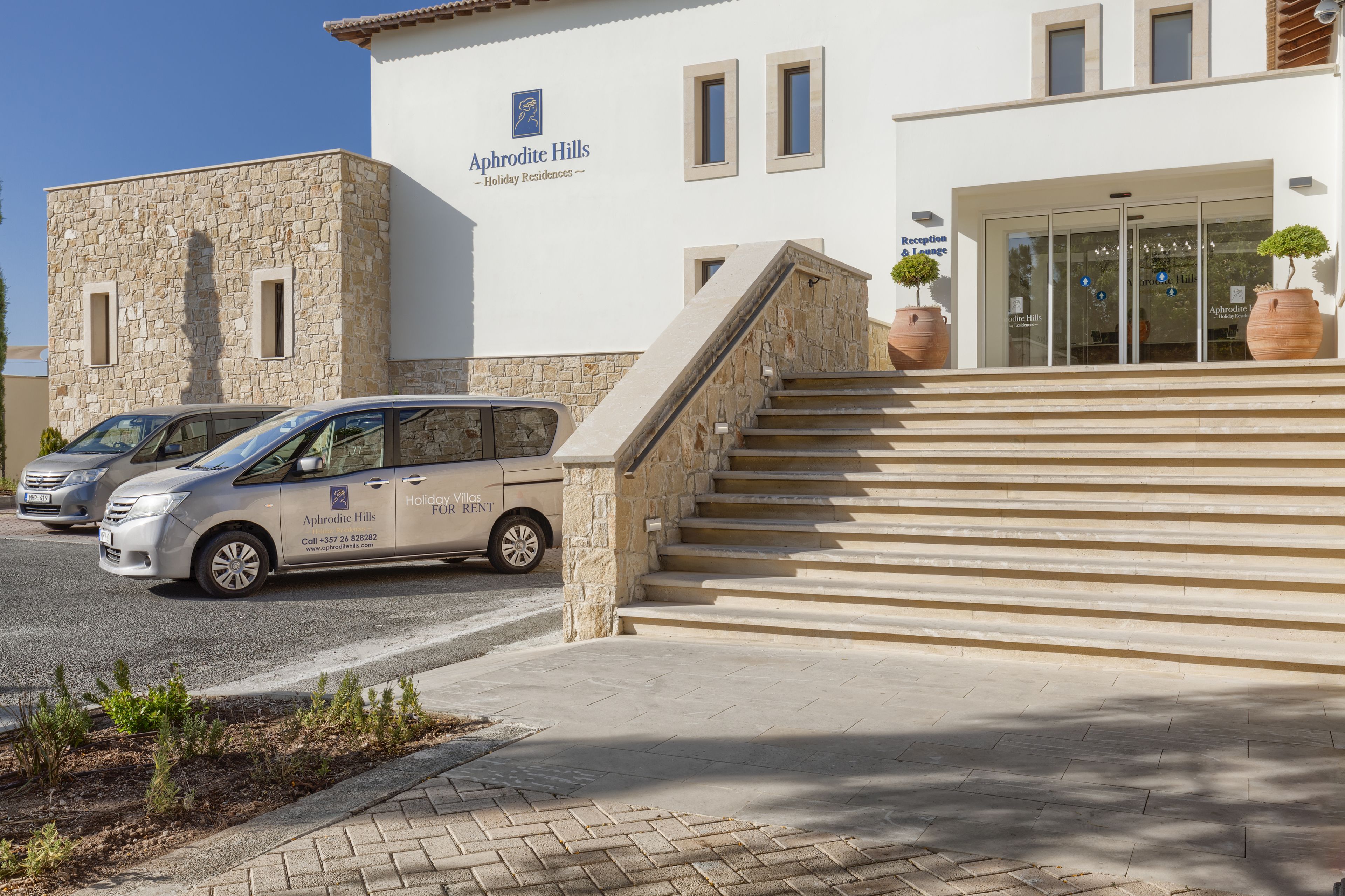 A building with a stone facade and a sign reading "Aphrodite Hills Holiday Residences."