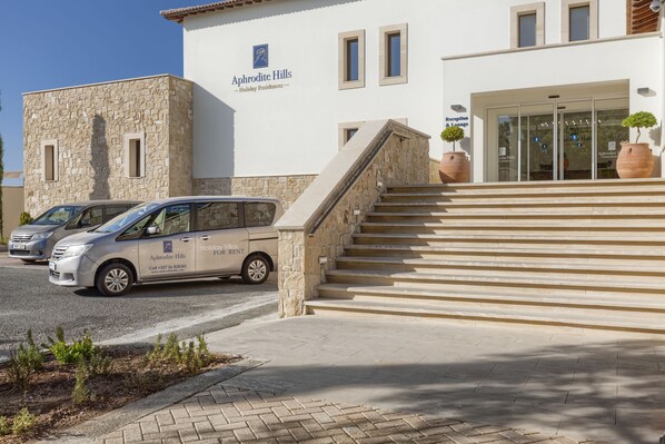 A building with a stone facade and a sign reading "Aphrodite Hills Holiday Residences."