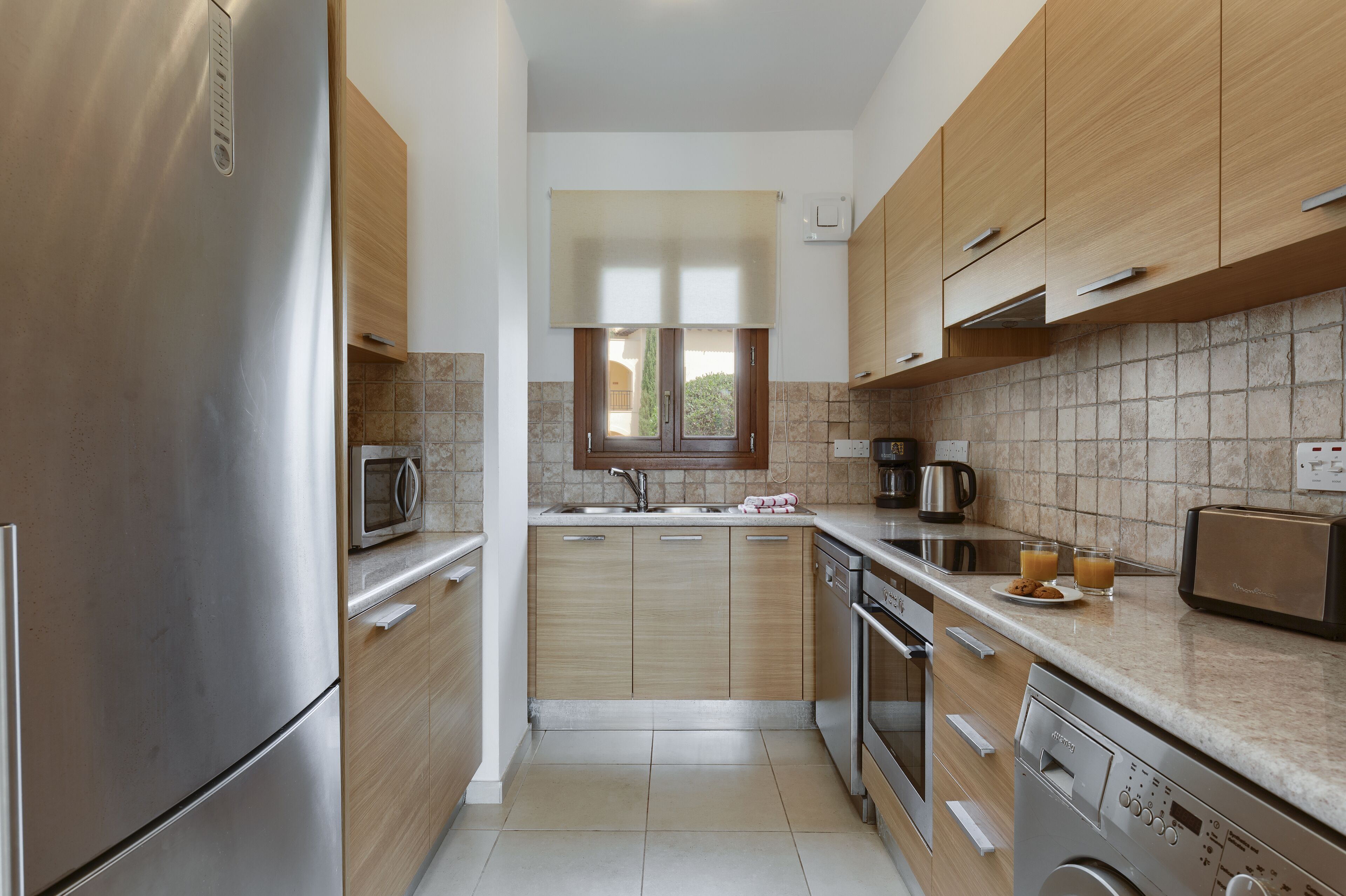 Una cocina moderna con electrodomésticos de acero inoxidable, armarios de madera y salpicadero de azulejos.