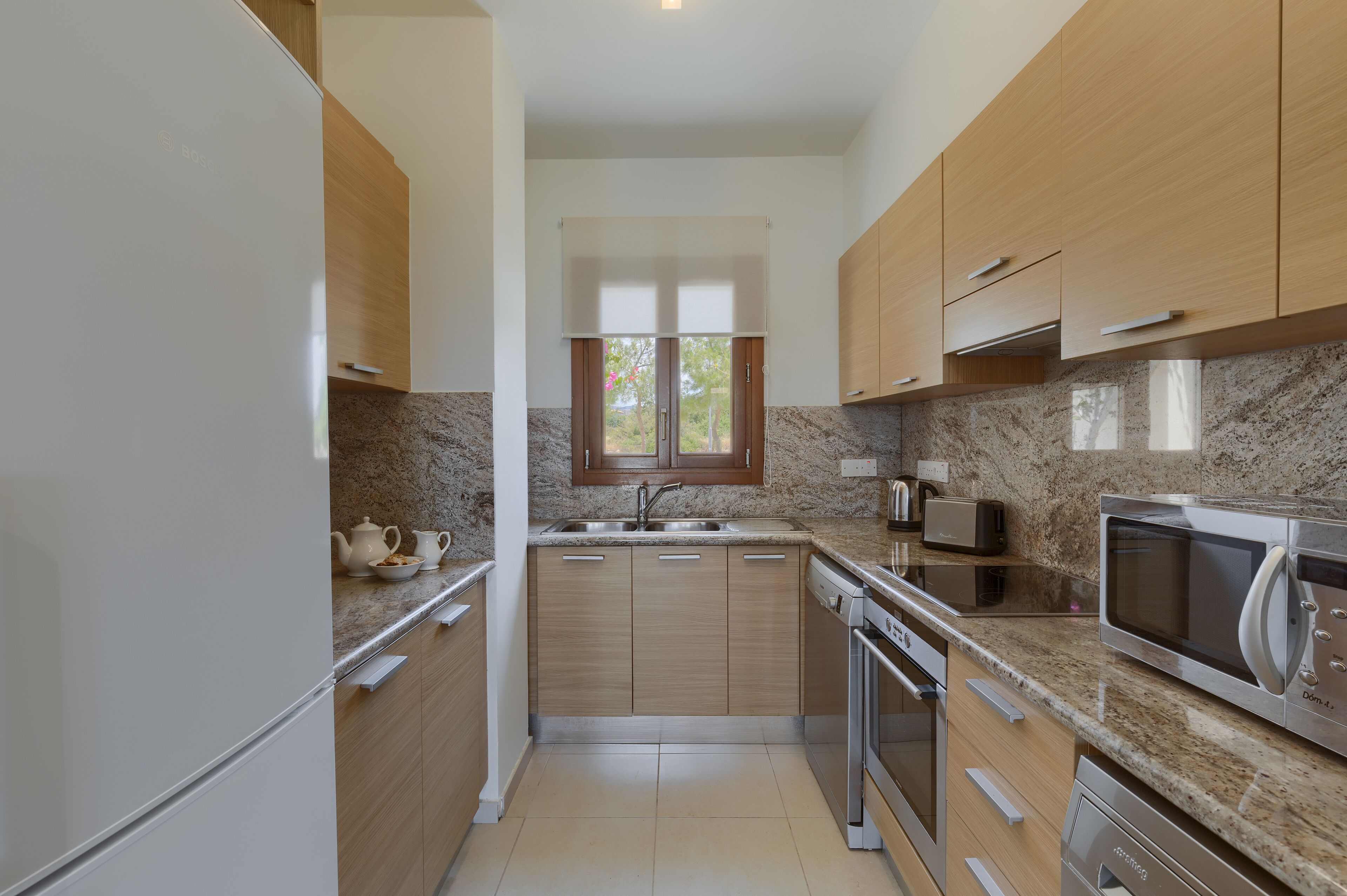 Eine moderne Küche mit Holzschränken, Granit-Arbeitsplatten, einem eingebauten Ofen und einer Mikrowelle.