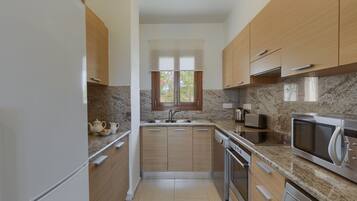 Eine moderne Küche mit Holzschränken, Granit-Arbeitsplatten, einem eingebauten Ofen und einer Mikrowelle.