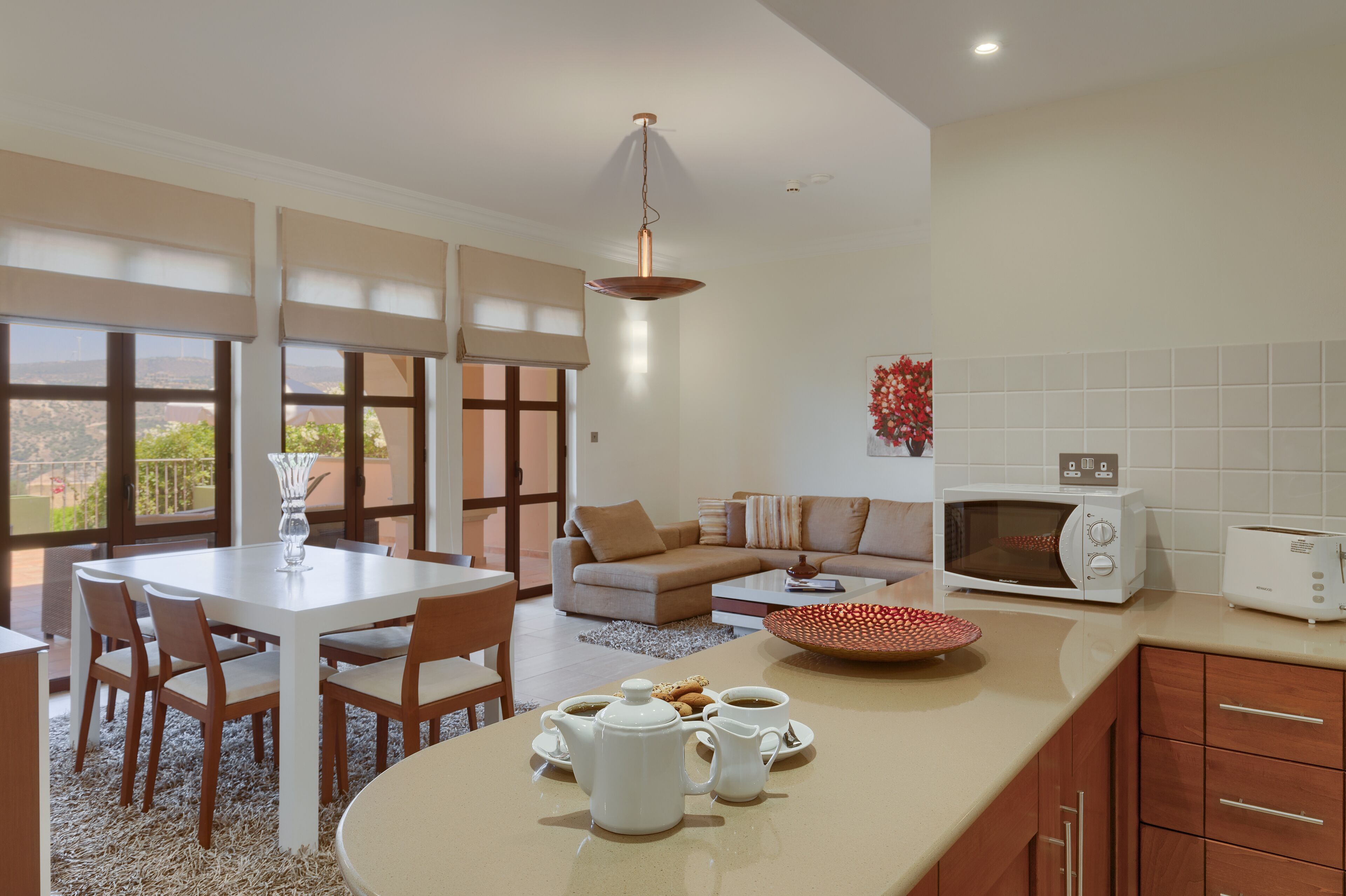 A modern kitchen with a dining area, a microwave, a toaster, and a coffee setup.