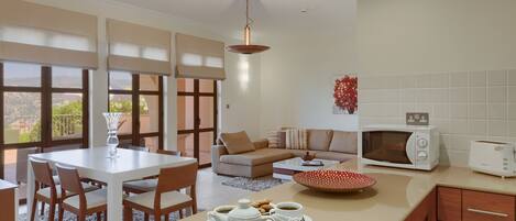 A modern kitchen with a dining area, a microwave, a toaster, and a coffee setup.
