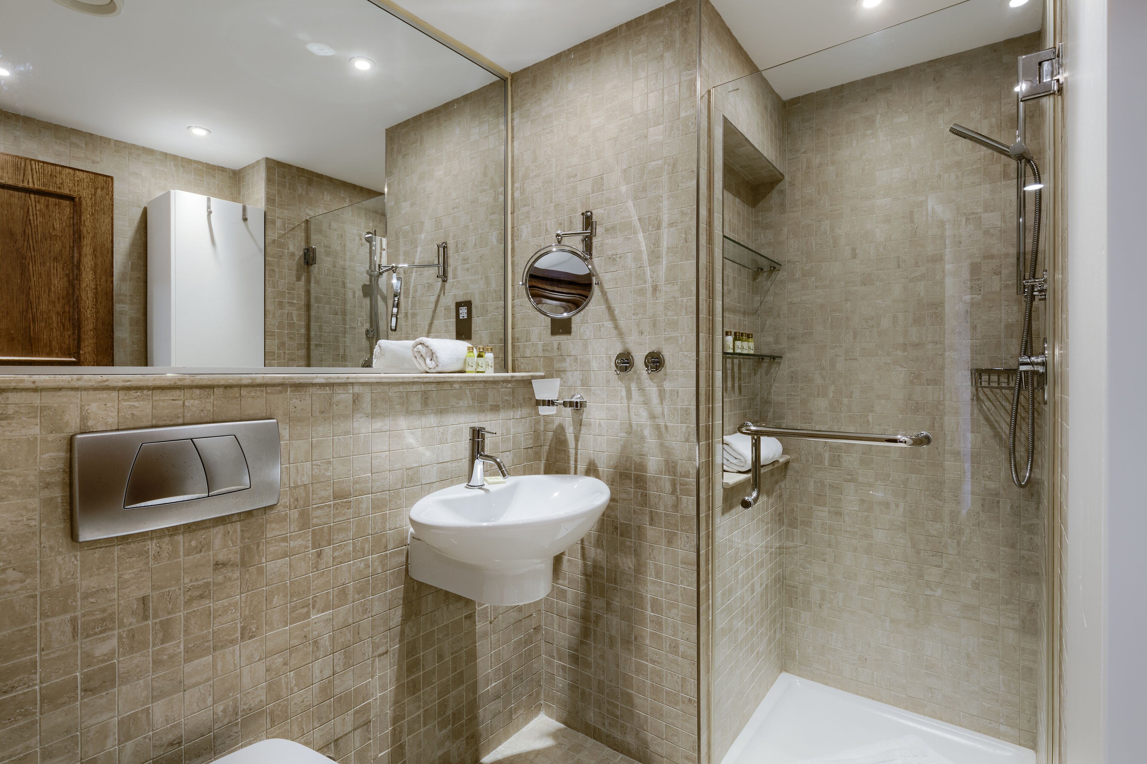 A modern bathroom with a glass shower enclosure, a built-in sink, and a toilet.