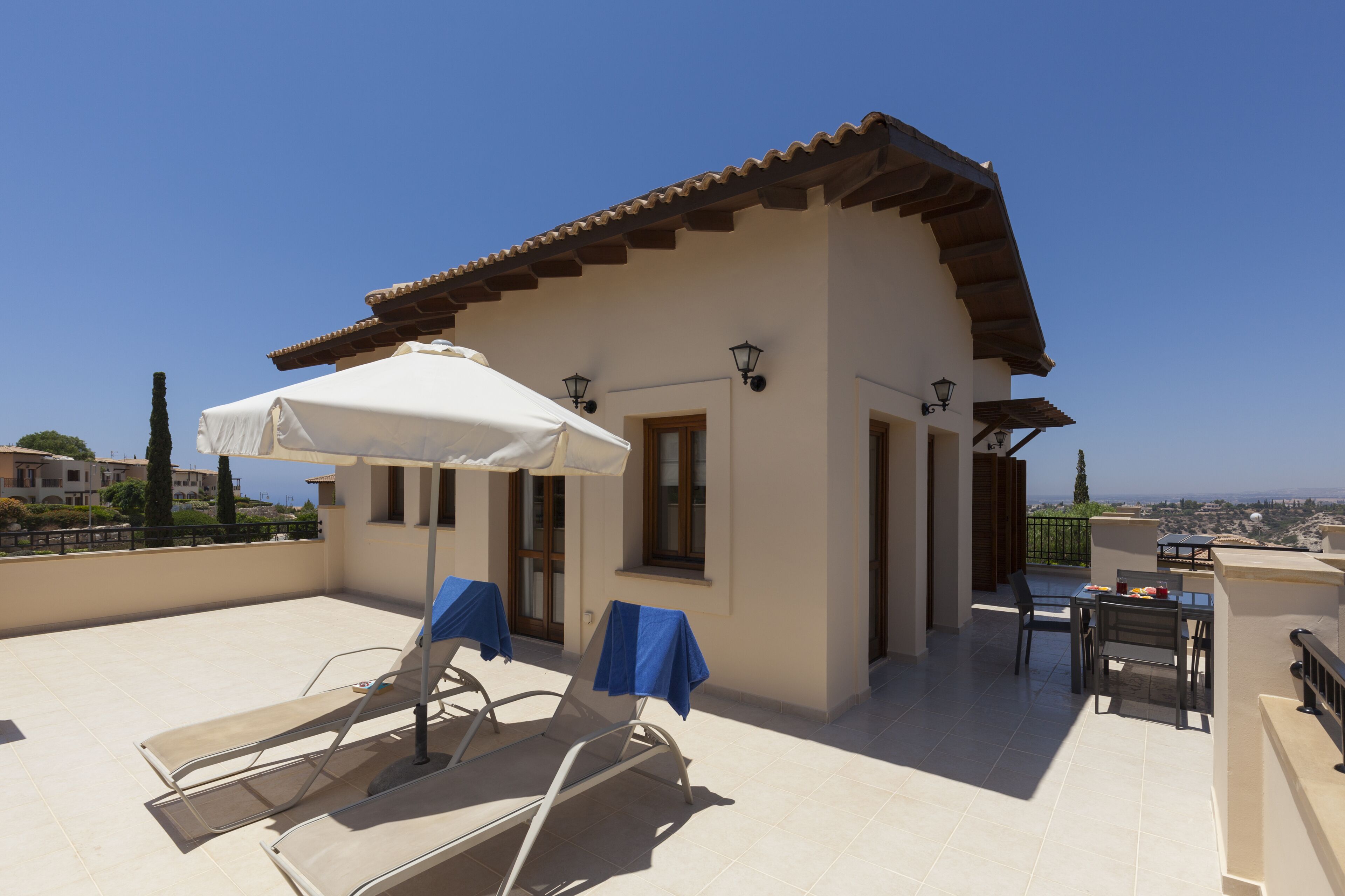 Terraza en la azotea con sillones, una mesa y una sombrilla.