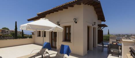 Terraza en la azotea con sillones, una mesa y una sombrilla.