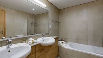 A modern bathroom with two sinks, a bathtub, and a large mirror.